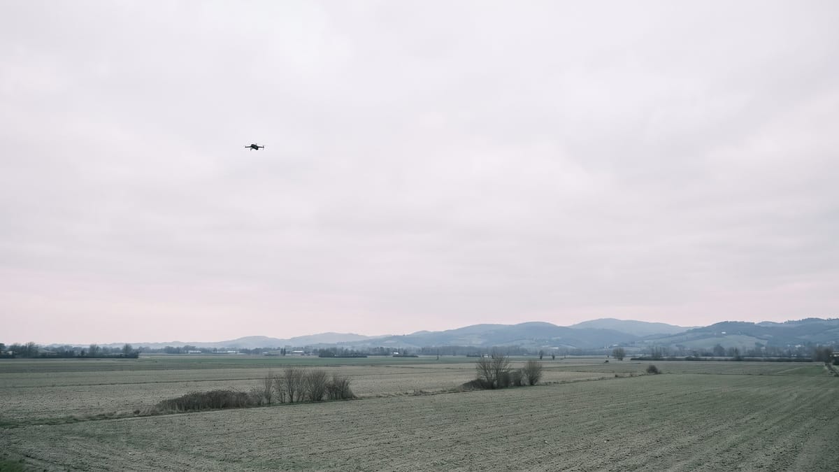 Pianura italiana al mattino con un piccolo drone in volo alto sulla sinistra
