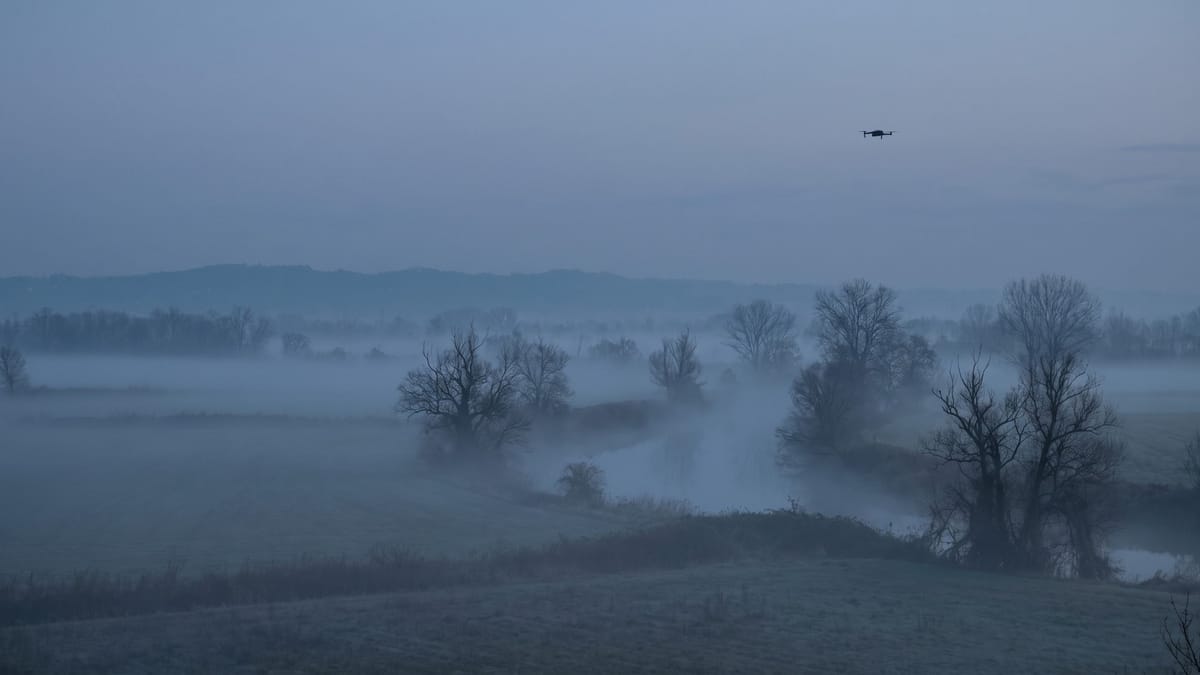Pianura italiana nella nebbia al crepuscolo con un piccolo drone in volo sulla destra