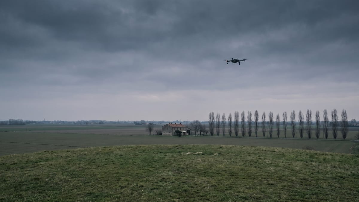 Campagna italiana sotto un cielo coperto con un piccolo drone in volo sulla destra